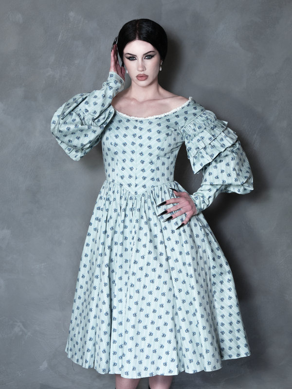 A striking vision of dark elegance, a female model embodies gothic glamour in a beautifully tailored, twilight-hued floral dress steeped in cinematic mystery.
