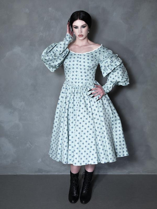 Enveloped in nocturnal mystery, a model styled in dramatic gothic clothing captures the ultimate essence of classic noir horror with a striking, romantic blue floral dress.