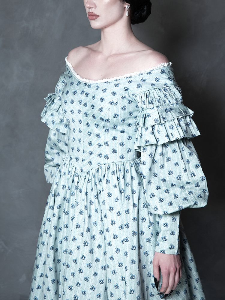 Radiating a sense of tragic romance and cinematic history, a female model wears a flowing piece of dark alternative apparel featuring a haunted, Victorian-inspired floral print.