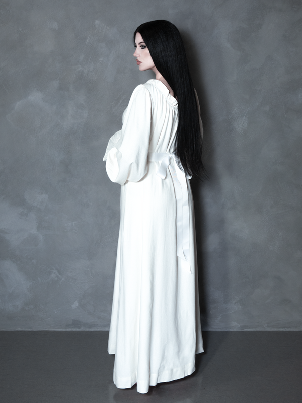 A gothic glamour icon channels the mysterious depth of a haunted manor while draped in a premium, pale ivory dress meant for the ultimate alternative aesthetic.