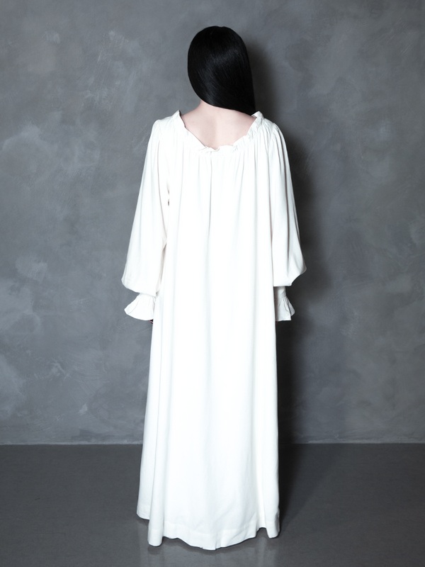 A model effortlessly blends regal comfort with a high-fashion Victorian Goth allure, showcasing a dramatic, ivory nightgown perfect for moonlit strolls.