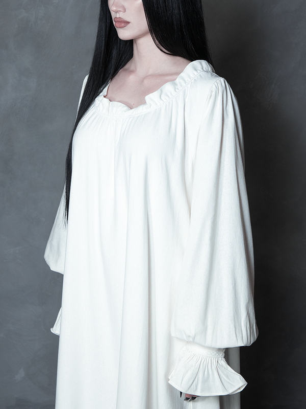 Infused with Whimsigoth enchantment and tragic romance, a female model presents a luxurious ivory dress that serves as a staple for any gothic glamour wardrobe.