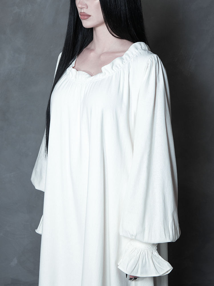 Infused with Whimsigoth enchantment and tragic romance, a female model presents a luxurious ivory dress that serves as a staple for any gothic glamour wardrobe.
