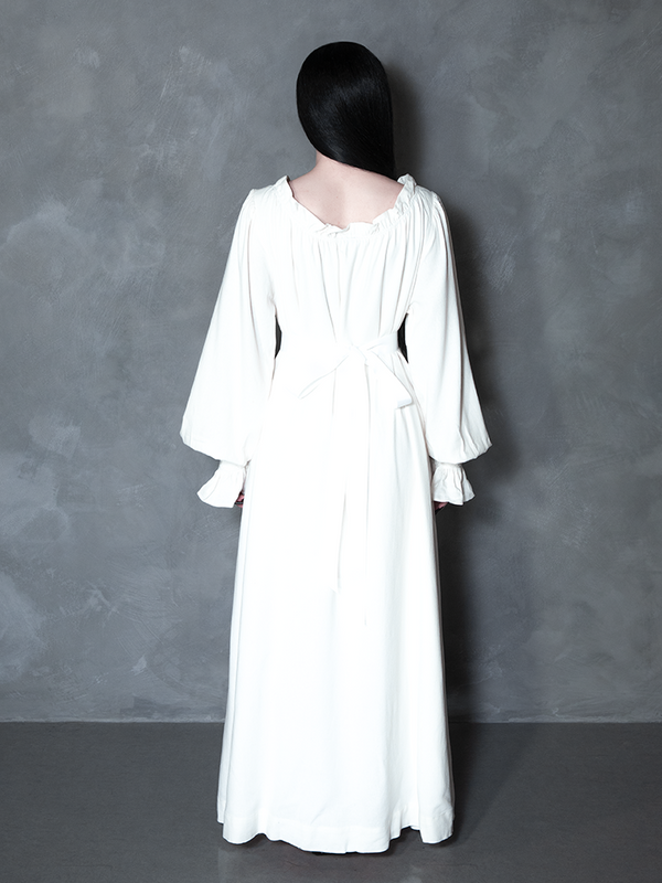 Exuding the essence of dark elegance and Whimsigoth moodiness, a female model layers her look with a hauntingly beautiful, cinematic bone-white gown.