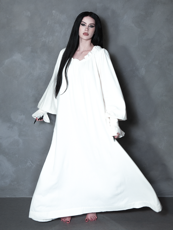 Enveloped in nocturnal mystery, a model styled in dramatic gothic clothing captures the ultimate essence of classic noir horror with a striking, romantic ivory sleeping dress.