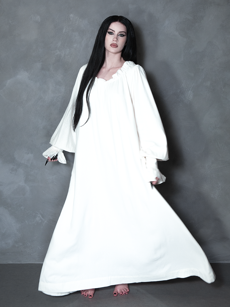 Enveloped in nocturnal mystery, a model styled in dramatic gothic clothing captures the ultimate essence of classic noir horror with a striking, romantic ivory sleeping dress.