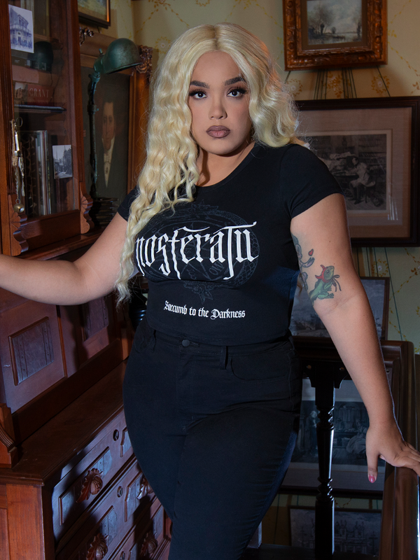 Infused with Whimsigoth enchantment and tragic romance, a female model presents a dark, luxurious graphic tee that serves as a staple for any gothic glamour wardrobe.