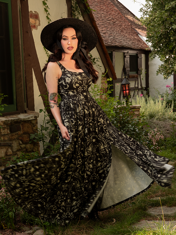 The Novella Maxi Dress in Cottage Witch Toile Print enchants with pastoral scenes steeped in mystery, flowing like a spell woven at dusk.