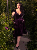 Micheline Pitt brings a touch of enchantment to a concealed garden, dressed in the Plum Baudelaire Swing Dress from La Femme en Noir, the gothic clothing brand.