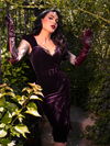 Micheline Pitt captivates in a clandestine garden, donning the Plum Baudelaire Wiggle Dress from the gothic clothing brand, La Femme en Noir.