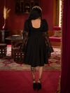 The dress’s flared skirt and dramatic cut evoke the mystique of old-world ballads.