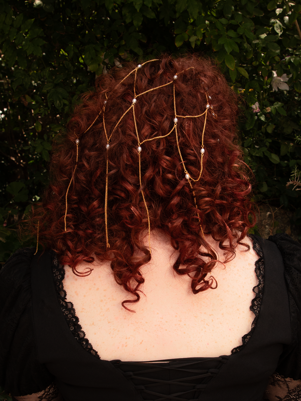 An echo of forgotten royalty, gold chains and pearls fall in radiant harmony, framing the hair in timeless allure. Lightweight construction ensures comfort; gently polish when needed.