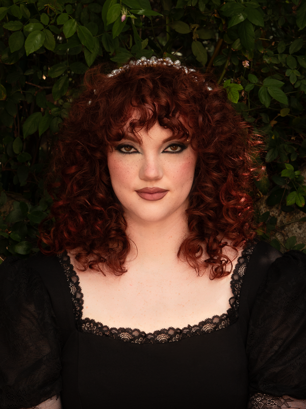 Resting atop loose curls, the pearl strands sway with subtle movement, transforming the headband into a statement of ethereal beauty and dramatic refinement.