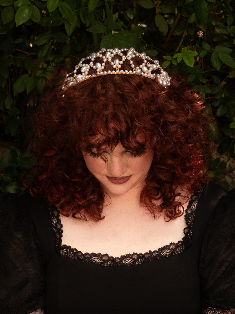 Framed against dark waves of hair, the gold headband spills delicate pearls in a graceful waterfall, blending celestial romance with timeless gothic sophistication.