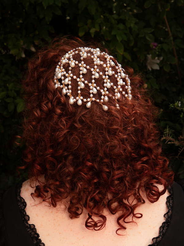 Styled beneath candlelit shadows, the cascading pearls glow against gold, creating a hauntingly elegant silhouette fit for soirées and nocturnal reverie.