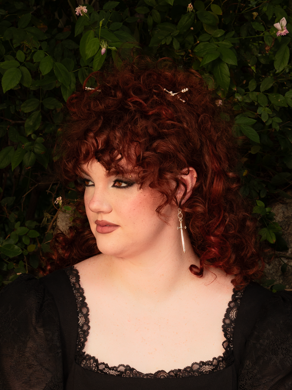 A gleaming whisper of rebellion, the Sword Hair Pin in Silver pierces through tresses like moonlight through shadow. Perfect for evening enchantments, it adds a deadly elegance to every look.