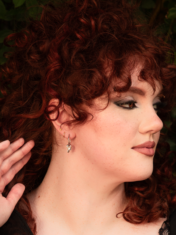 Infused with a sense of mysterious sophistication, a female model captures the spirit of traditional Victorian Goth fashion with these eye-catching silver skull hoop earrings.