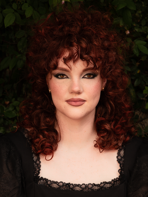 Exuding an enchanting Whimsigoth energy, a female model balances mystery and sophistication while wearing delicate yet striking silver skull stud earrings.