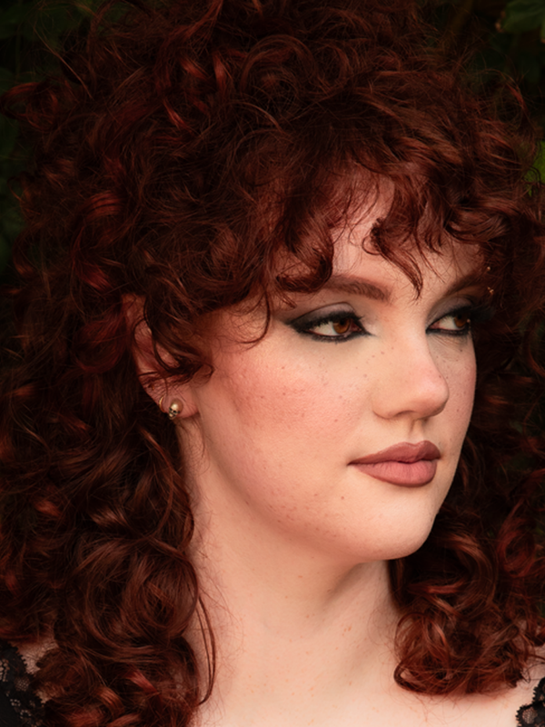 A female model beautifully merges contemporary gothic style clothing with romantic elements, her presence accented by the haunting allure of silver skull stud earrings.
