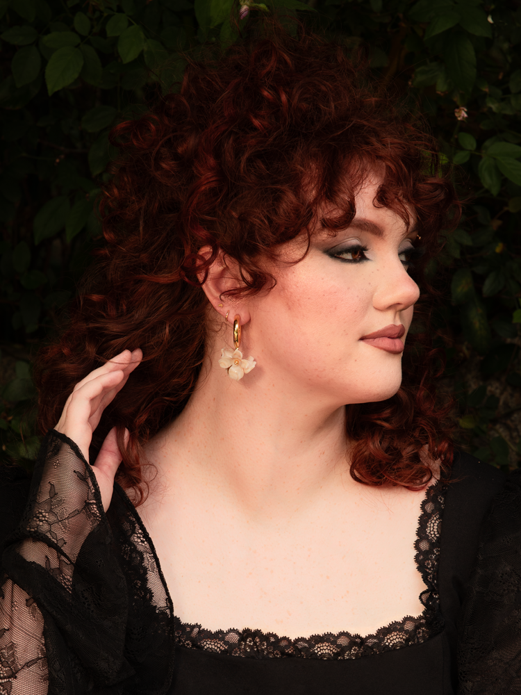 Worn by a model with an elegant updo, the earrings catch the light with every movement—golden petals framing her face like whispers of a forgotten summer.