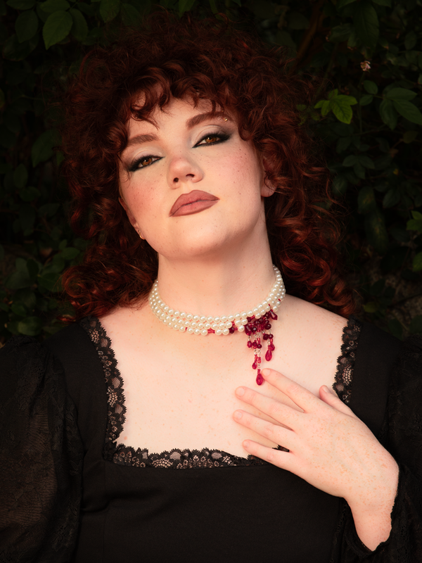 Layers of pristine white strands encircle the neck as red blood crystals glisten like forbidden gems, creating a striking contrast of innocence and dark desire.