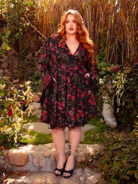 The Styx Wrap Dress with Fringe in Pomegranate Print is a hauntingly beautiful creation. Its deep red pattern and flowing silhouette evoke the spirit of gothic poetry and forbidden love.