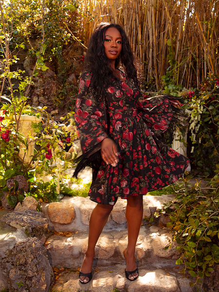 The Styx Wrap Dress with Fringe in Pomegranate Print is a darkly romantic creation. With its deep red hues and flowing silhouette, it evokes a sense of mystery and timeless allure.