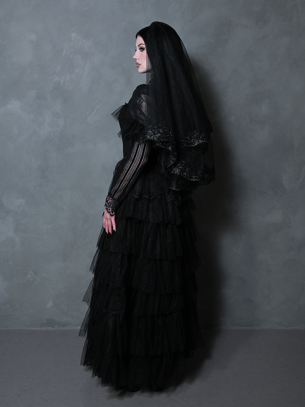 Female model donning a romantic black gothic masterpiece exuding timeless Victorian dark allure.