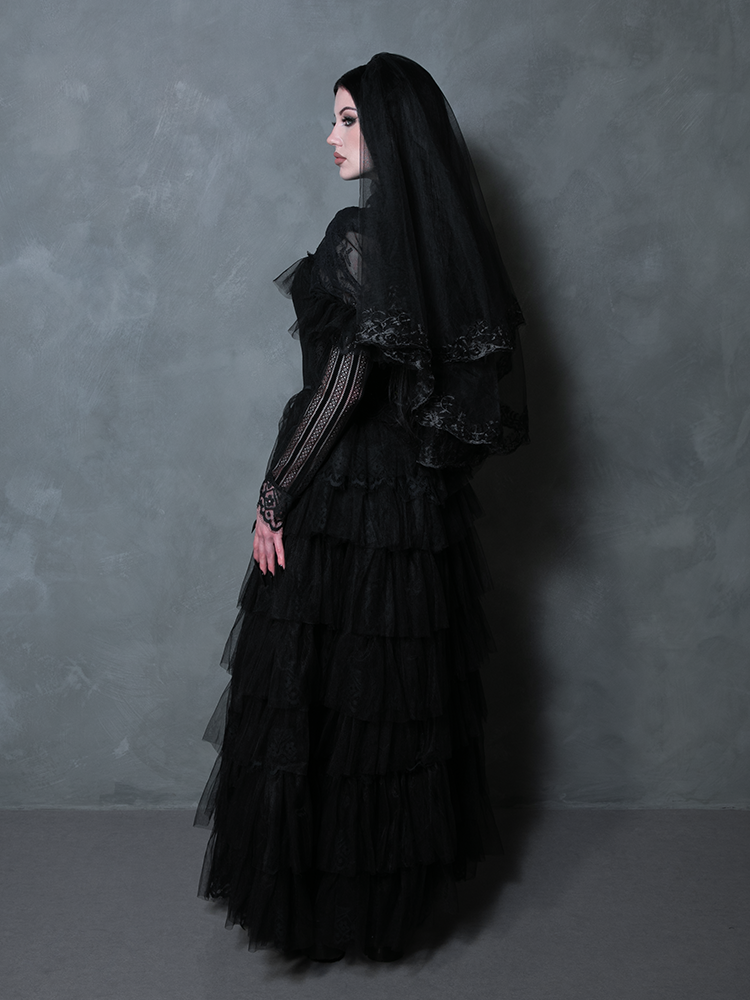 Female model donning a romantic black gothic masterpiece exuding timeless Victorian dark allure.