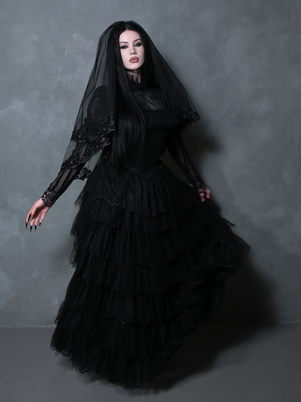 A beautifully styled female model donning a majestic black alternative bridal gown with dark allure.
