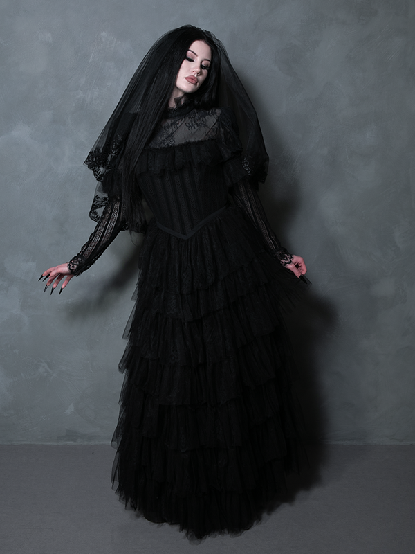 Woman in a stunning black floor-length gown radiating dark elegant glamour and mysterious charm.