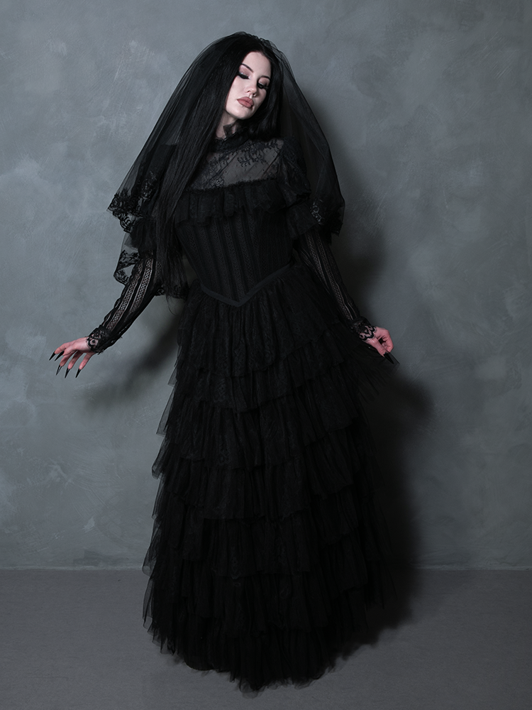 Woman in a stunning black floor-length gown radiating dark elegant glamour and mysterious charm.