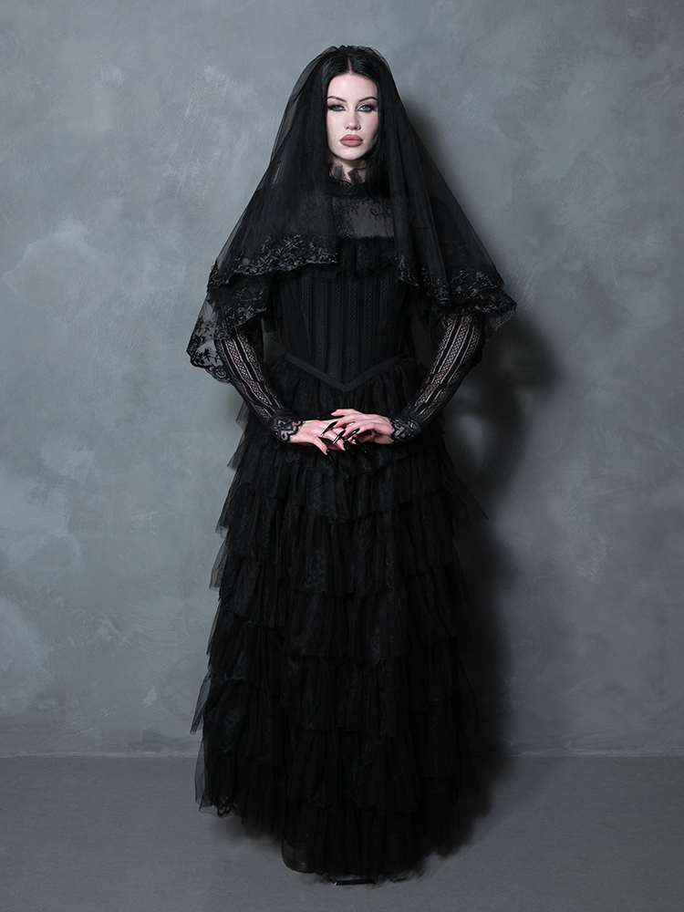 A stunning female model styled in a dramatic black gothic gown exuding Victorian elegance.