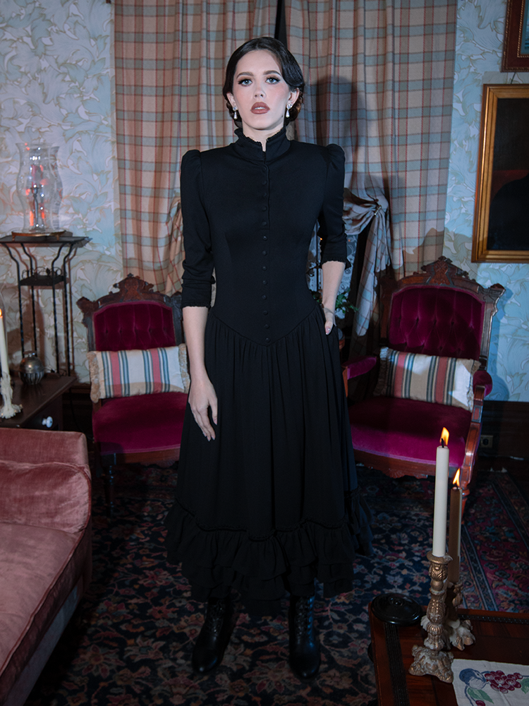 Infused with Whimsigoth enchantment and gothic glamour, a female model steps out in a breathtaking black Victorian dress.