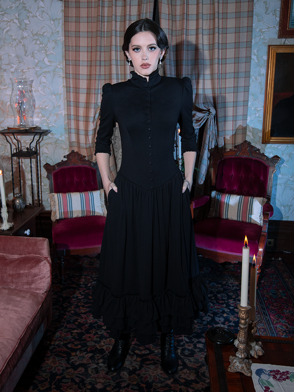 A striking display of gothic glamour as a female model wears an exquisite black dress layered with romantic, vintage-inspired charm.