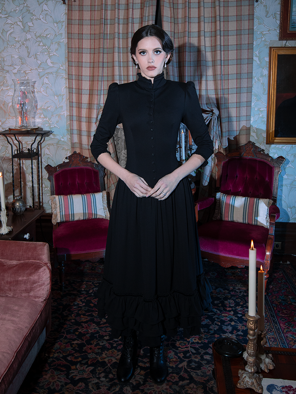 A female model presents an aura of dark elegance and poetic melancholy while wearing an ornate black gothic dress.