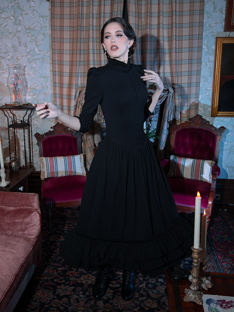 A classic vision of dark elegance, a female model embodies the essence of Victorian Goth styling in a hauntingly beautiful black dress.