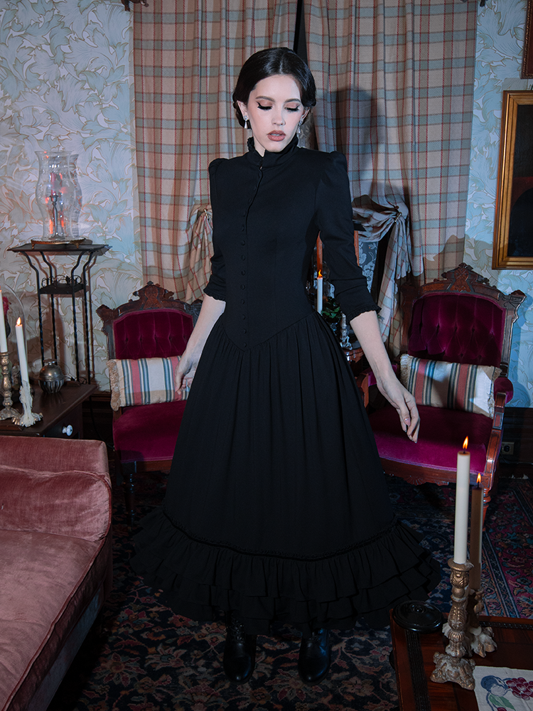 A female model wanders through a dreamscape of gothic glamour, draped in a cascading black Victorian Goth dress.