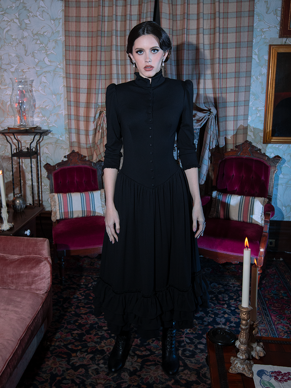 A female model beautifully interprets the dark elegance of classic gothic clothing in a sweeping, romantic black dress.