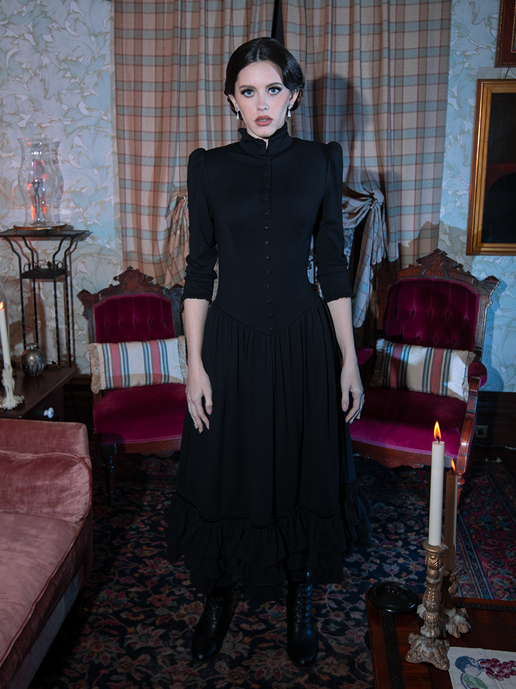 A female model beautifully interprets the dark elegance of classic gothic clothing in a sweeping, romantic black dress.