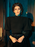 With an air of gothic elegance, female models strike various poses while showcasing the Victorian Cycling Pullover Sweater in Black.
