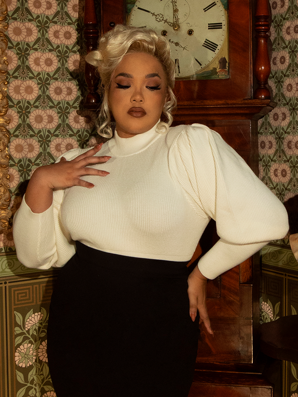 A nod to Victorian cycling fashion, this ivory pullover exudes sophistication with its structured bodice, puffed shoulders, and ornate button detailing.

