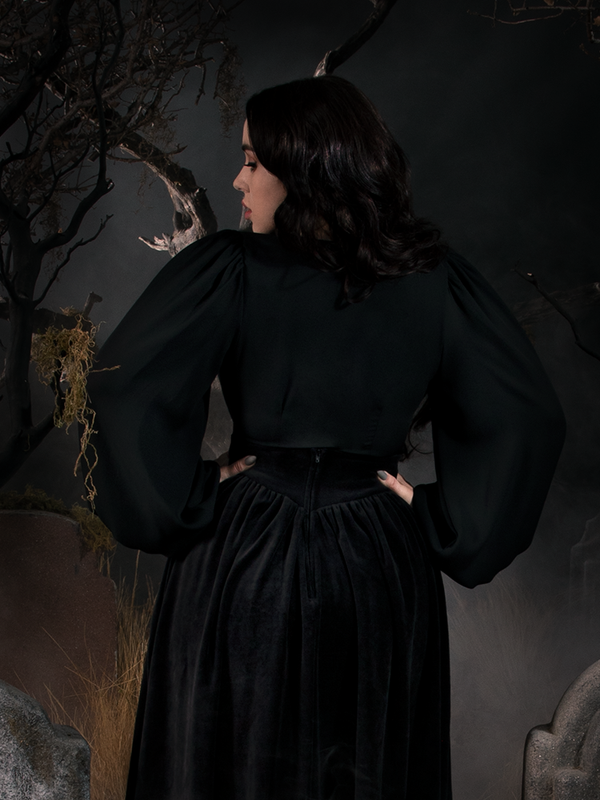 Rachel turned away from the camera to show off the back of the Georgette Wrap Top in Black.