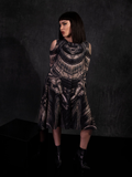 Micheline Pitt standing in the Alien™ Xenomorph Trapeze Dress while looking off to the side and holding her arms behind her back.