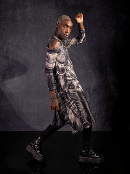 Braxton Holmes posing in black vinyl boots, black jeans and the Alien™ Xenomorph Trapeze Dress.