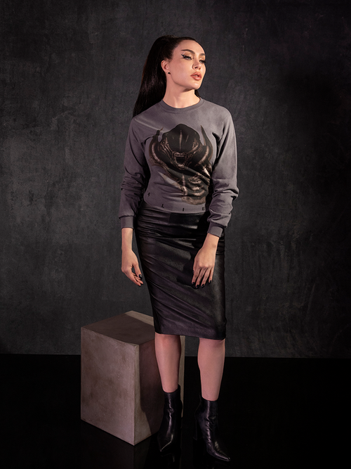 Micheline Pitt standing in front of a black and grey slate background while wearing the Alien™ Xenomorph Vintage Long Sleeve in Grey.