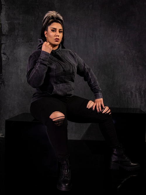 Jyoti Kaur modeling the Alien™ Retro Poster Logo Hoodie with black ripped jeans and matching combat boots.