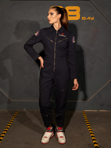 KJ standing in front of a bay door on a spaceship while wearing the ALIEN Ripley Flight Suit in Navy from La Femme en Noir.