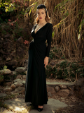 Micheline Pitt stands in nature while modeling the Art Deco ruched gown in black from La Femme En Noir.
