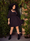 The Solstice Babydoll Dress in Black Chiffon being worn by Ashley as she sways around to show off the flowy skirt.